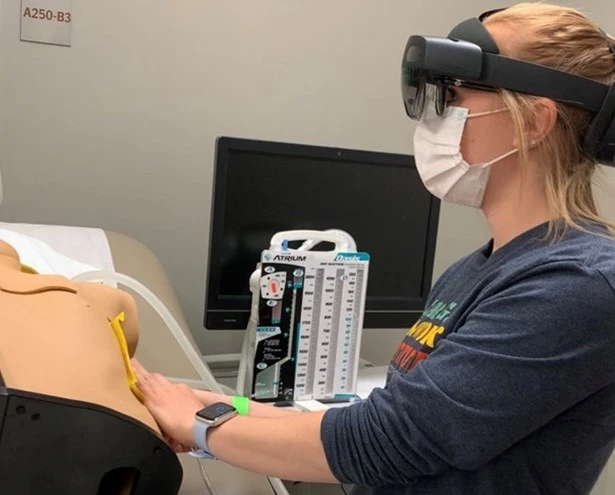 Nursing student conducting guided training on a mannequin with HoloLens 2.