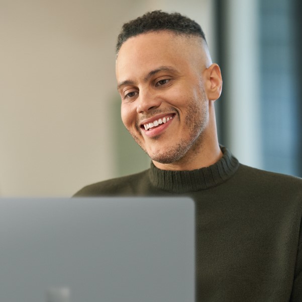 A man who is smiling and looking at a laptop