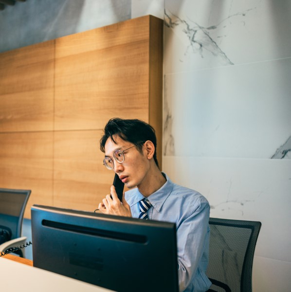 An employee sitting at a computer, on a phone