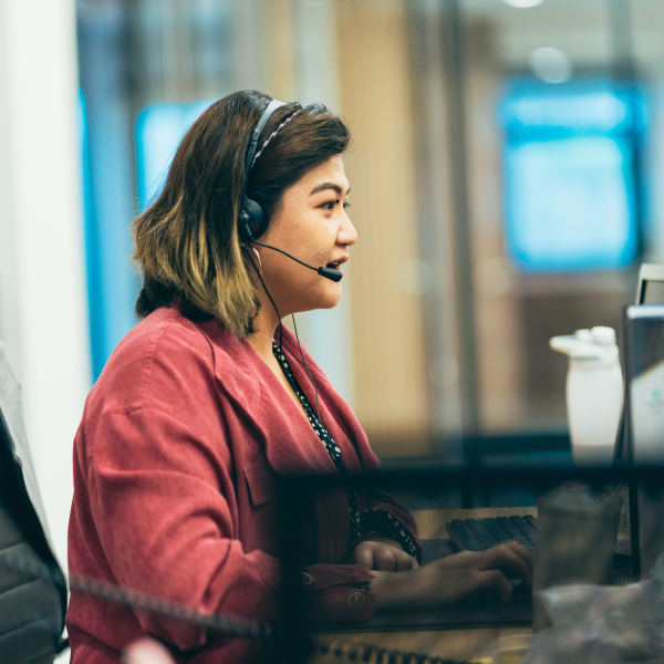 A woman wearing a headset and sitting at a computer